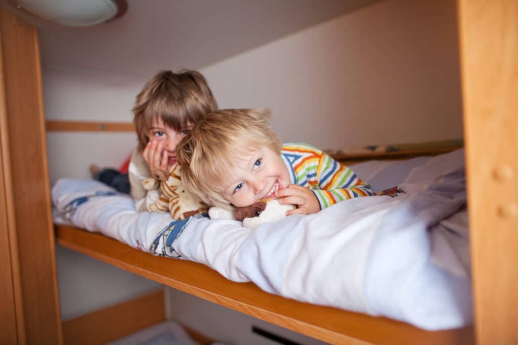 Portrait of happy young boy with brother lying on bunk bed in their RV