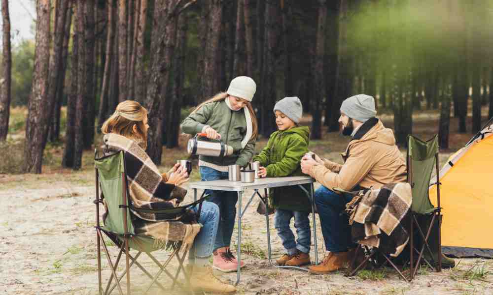 family sitting around a table camping