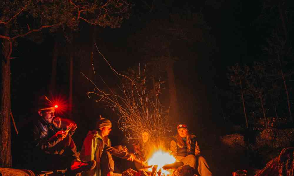 People sitting around a campfire with sparks coming out of it